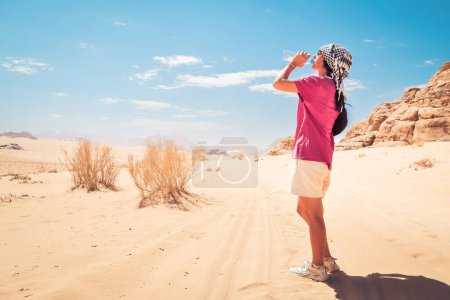 Téléchargez les photos : Femme caucasienne soif boire de l'eau fraîche froide dans la chaleur extrême dans le désert de rhum oued chaud en plein air sur le sentier de randonnée - en image libre de droit
