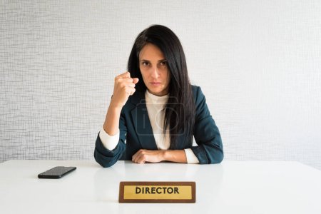 Photo for Young cute caucasian brunette business woman director in office show fist to camera at work for employee resentful angry serious look at camera. POV employee - Royalty Free Image