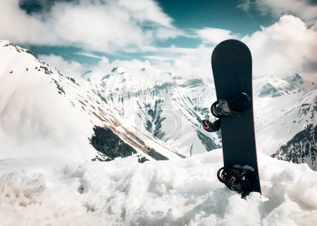 Foto de Soporte de snowboard en nieve con fondo de hermosas montañas blancas del Cáucaso en el mirador superior de la estación de esquí de Gudauri en invierno. Georgia esquí destino de vacaciones de invierno - Imagen libre de derechos