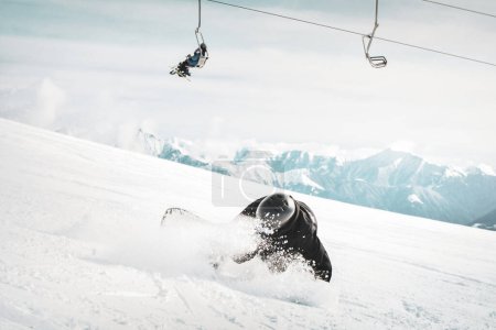Photo for Snowboarder is riding with snowboard from powder snow hill very fast and fall down - Royalty Free Image