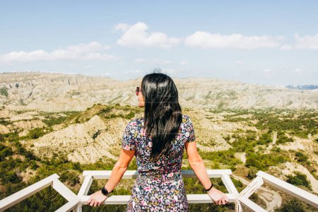 Téléchargez les photos : Femme brune se tient sur le point de vue de la plate-forme et regarde à gauche sur le beau paysage de la réserve naturelle de Vashlovani - en image libre de droit