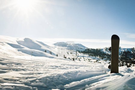 Téléchargez les photos : Black base of snowboard in a snow with white mountains in the background. Concept of new ski season. - en image libre de droit