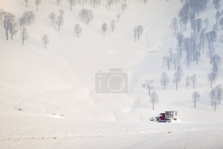 Téléchargez les photos : Snowcat with cabin to take skiers snowboarders freeride downhill in remote caucasus mountains. Ratrak in - en image libre de droit