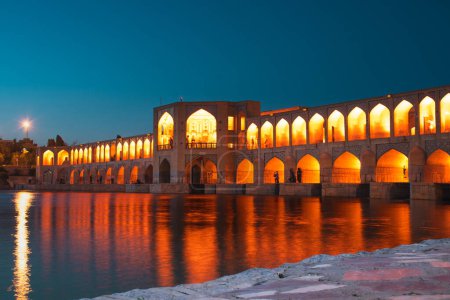 Photo for Isfahan, Iran - 15th june, 2022: tourist muslim visit Old Khajoo bridge at night, across the Zayandeh River in Isfahan, Iran. - Royalty Free Image
