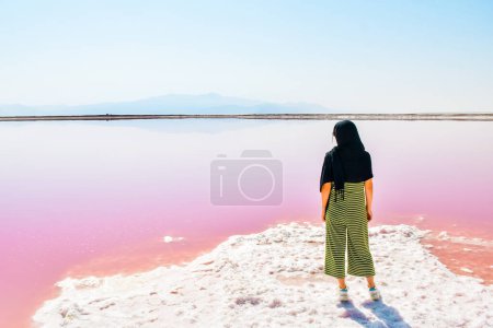 Foto de Turista mujer caucásica de pie en Maharlu rosa orilla del lago de sal. Destino de viaje Irán en Shiraz - Imagen libre de derechos