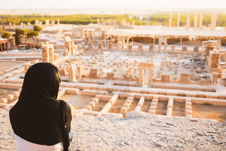 Photo for Tourist woman visit famous destination sit on viewpoint above Persepolis. Explore famous historical persian city of Persepolis in Shiraz, Iran - Royalty Free Image