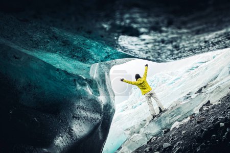 Téléchargez les photos : Une touriste se tient près du magnifique glacier Fjallsjakull en Islande par temps couvert. Grottes de glace en Islande. Vue depuis une petite grotte vide - en image libre de droit