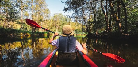 Photo for Back Rear View strong caucasian woman rowing Kayaking In Beautiful Lithuania countryside river - Zemeina. Action Camera POV Of Girl Paddling On canoe. Active holidays fun outdoors - Royalty Free Image