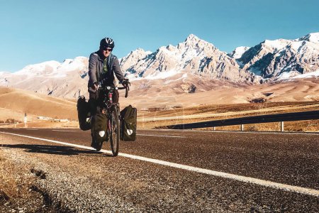 Téléchargez les photos : Cycliste caucasien mâle vélo sur route asphaltée en Turquie mountains.Snowy pics en plein air - en image libre de droit