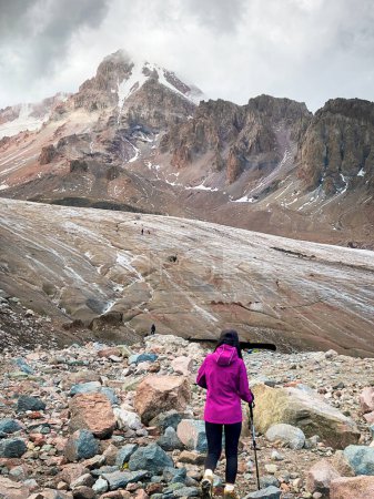 Photo for Brave woman hiker climb up glacier trail in KAzbegi National Park at gergeti glacier trail.Mountain KAzbek climb route - Royalty Free Image