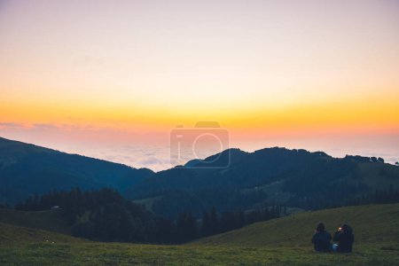 Photo for Bakhmaro, Georgia - 6th august, 2022 : Sunset over clouds in georgia caucasus mountains with tourist girl sit enjoy sunset have fun together outdoors on vacation - Royalty Free Image