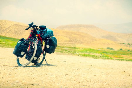 Touring bicycle stand on scenic gravel road in nature. Fully loaded touring machine with copy space background