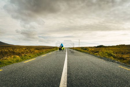 Cyclist bicycle touring drive turn around on wild atlantic way road in Ireland. Travel adventure outdoors
