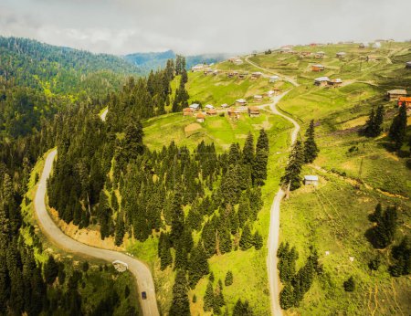Aerial view car on road and old houses on hilltop in Bakhmaro village in summer. FAmous travel landmark summer resort in caucasus mountains. Holiday destination in Guria, Caucasus