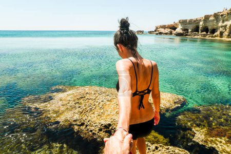 Hermosa mujer caucásica de pie en roca mirador disfrutar de aguas cristalinas y paisaje marino mediterráneo en las vacaciones de verano. Felicidad y viajes explorar concepto