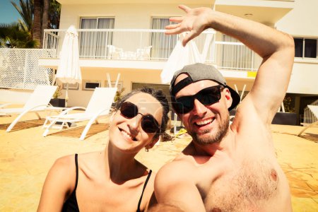 Feliz pareja viajera haciendo selfie en el baño de sol del hotel. Vacaciones de verano. Humor romántico. Elegantes gafas de sol. Feliz risa caras emocionales hipster multirracial. Chipre vacaciones