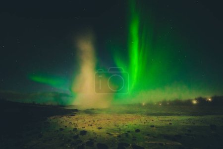 Strokkur geysir erupción en la noche con las luces del norte de fondo. Círculo Dorado, Islandia