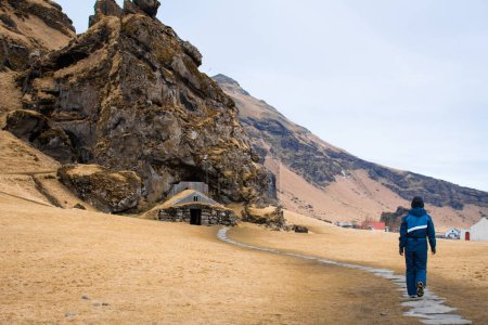 Femme Touriste visiter la maison de gazon et Drangurinn Rock dans le sud de l'Islande. Montagnes Eyjafjll près de Ring Road, Route 1. Maisons de gazon liées aux elfes, folklore, sagas et légendes