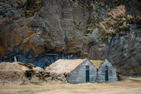 Maison en gazon au pied du rocher Drangurinn dans le sud de l'Islande. Montagnes Eyjafjll dans le sud de l'Islande près de Ring Road, Route 1. Maisons de gazon liées aux elfes, folklore, sagas et légendes
