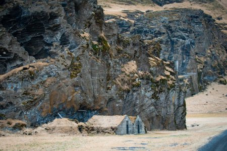 Maison en gazon au pied du rocher Drangurinn dans le sud de l'Islande. Montagnes Eyjafjll dans le sud de l'Islande près de Ring Road, Route 1. Maisons de gazon liées aux elfes, folklore, sagas et légendes