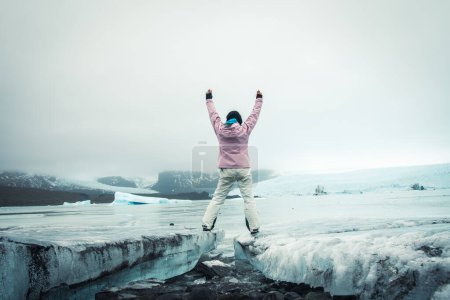 Tourist woman visitor stand by beautiful Fjallsjokull glacier on ice in Iceland. Inspirational travel explore holidays Iceland concept