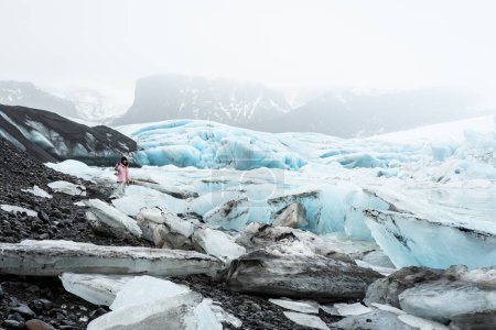 Tourist woman stand by beautiful Fjallsjokull glacier on ice in Iceland. Inspirational travel explore holidays Iceland concept