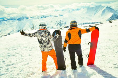Couple Male snowboarders friends excited enjoy panorama in winter skiing outfit . Mountains background with tourist enjoy holidays spreaded hands