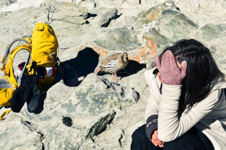 Junge kaukasische Wanderin ruht sich auf dem Chola-Pass im Himalaya aus und empfindet niedrigen Sauerstoffgehalt als Schwindel und Schwäche