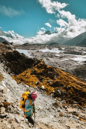 Woman trekker trekking to Gokyo Ri in Sagarmatha national park with mountains background. EBC trekking detour. Everest base camp trekking in fall, autumn in sunny dry weather