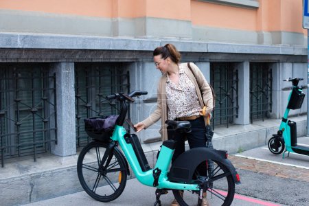 Téléchargez les photos : Une jeune femme fait du vélo à louer. Location de vélos et scooters. Service de location de vélos - en image libre de droit