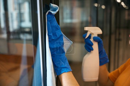 Téléchargez les photos : Employé d'un service de nettoyage utilise un spray spécial et une serviette pour le lavage et la désinfection dans l'espace de bureau - en image libre de droit