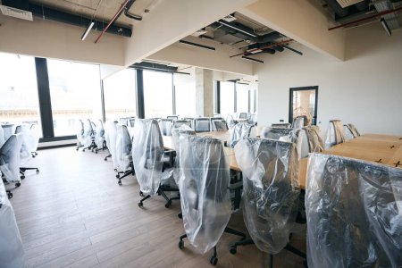 Téléchargez les photos : Coworking dans le centre de bureau après nettoyage général, salle blanche avec mobilier couvert, design high-tech - en image libre de droit