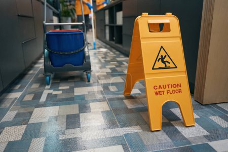 Photo for Warning sign Caution wet floor stands in office on the floor, wet cleaning is carried out in the room - Royalty Free Image