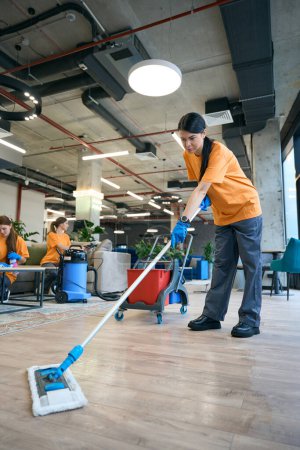 Photo for Cleaning company employees use modern devices, a professional vacuum cleaner, a special mop - Royalty Free Image