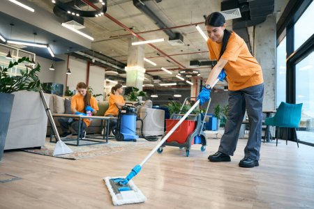 Photo for Cleaning company employees are dressed in work clothes, they use a professional vacuum cleaner, a special mop - Royalty Free Image