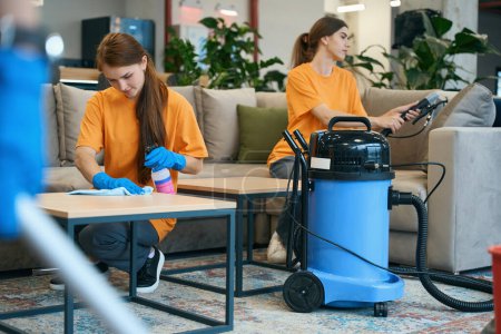 Photo for Employees of the cleaning company make a thorough cleaning of furniture with a vacuum cleaner and special tools - Royalty Free Image