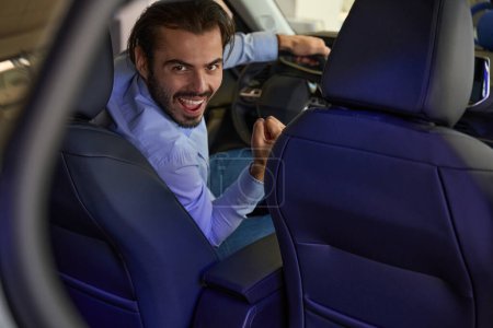 Photo for Smiling cheerful young driver sitting behind steering wheel of brand new motor vehicle - Royalty Free Image