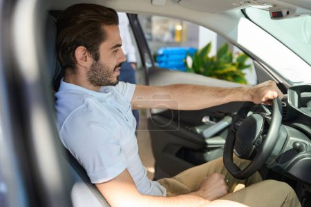 Téléchargez les photos : Jeune acheteur potentiel souriant assis au volant d'un véhicule automobile moderne - en image libre de droit