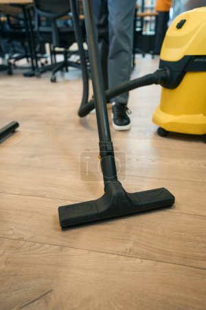 Téléchargez les photos : Nettoyage d'un espace de coworking avec un aspirateur par un employé d'une entreprise de nettoyage - en image libre de droit