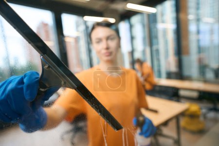 Photo for Women from the cleaning service use a glass scraper, vacuum cleaner, they are wearing work clothes and protective rubber gloves - Royalty Free Image