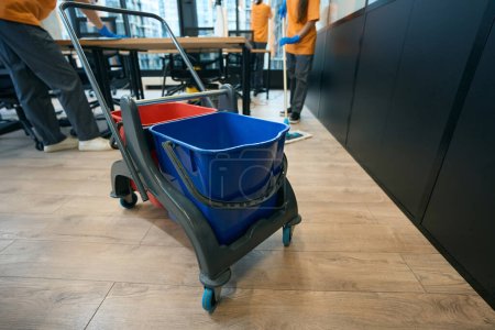 Photo for Process of cleaning in the coworking area, workers use a mop, buckets, rags and a special cart - Royalty Free Image
