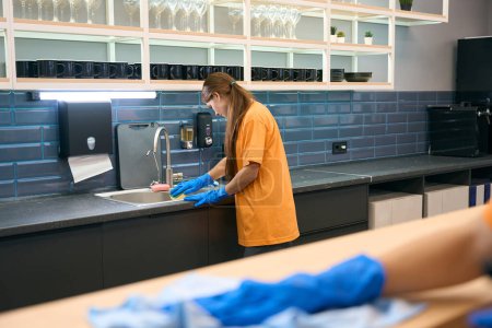 Photo for Workers in uniform clean and disinfect surfaces in the kitchen area, they use special sponges and wipes - Royalty Free Image