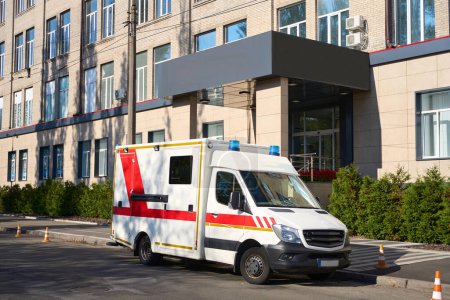 Foto de En el estacionamiento en la entrada principal del hospital, hay una furgoneta blanca con marcas rojas para que la ambulancia salga - Imagen libre de derechos