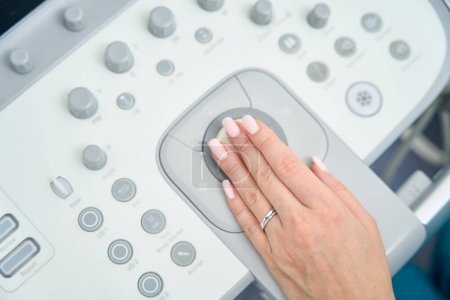 Foto de La mujer colocó su mano con una manicura limpia de color desnudo en la máquina para un examen de ultrasonido de la paciente - Imagen libre de derechos
