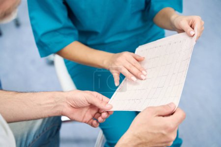 Photo for Two people sit next to a friend and discuss the results of a heart test - Royalty Free Image