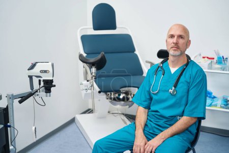 Foto de Ginecólogo serio está sentado en un consultorio médico entre el equipo profesional y vestido con un uniforme - Imagen libre de derechos