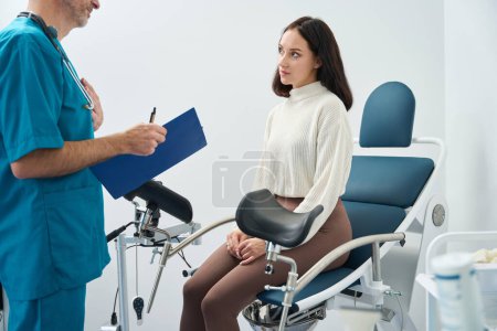 Téléchargez les photos : Femme inquiète écoute attentivement les recommandations d'un travailleur médical tout en étant assis en face de lui - en image libre de droit