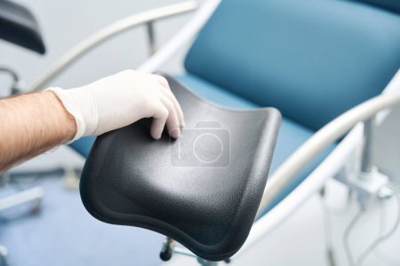 Foto de Mano de un oficial médico en un guante estéril ajusta el detalle de examen silla femenina - Imagen libre de derechos