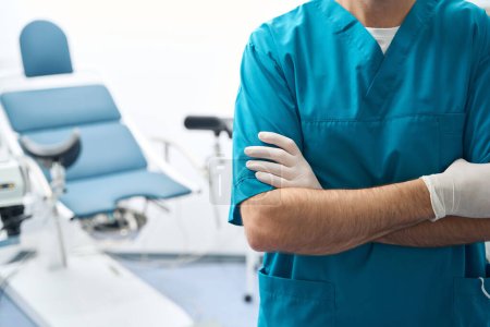 Sanitätsoffizier steht in Uniform neben einem Behandlungsstuhl, während sterile Handschuhe über seine Hände gezogen werden