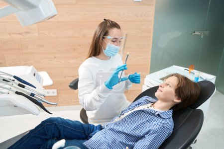 Photo for Woman dentist holding syringe with anesthesia for smiling teen patient - Royalty Free Image